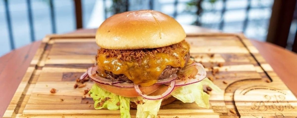 Hambúrguer de frango empanado, com queijo derretido por cima e salada. Uma ótima opção para saborear no Dia Mundial do Hambúrguer.