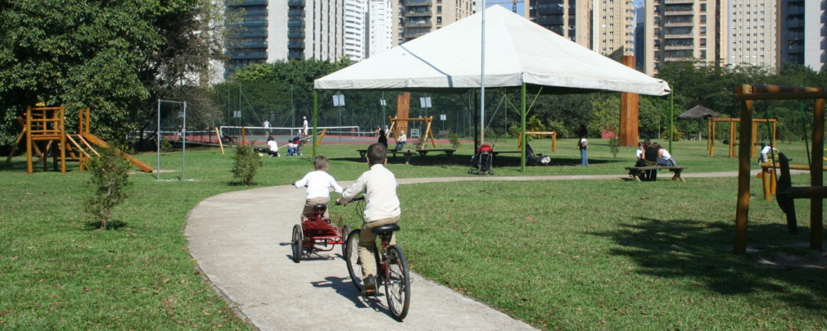 Duas pessoas passeando de bicicleta em SP na ciclovia do Parque Villa-Lobos. 