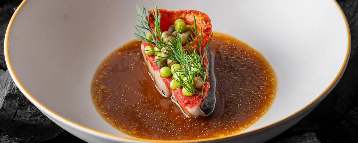 Prato fundo com caldo e carne, empratados de maneira delicada. 