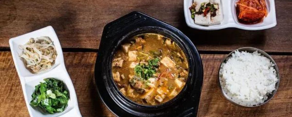 Mesa com ensopado, arroz e comidas típicas da cultura coreana. 