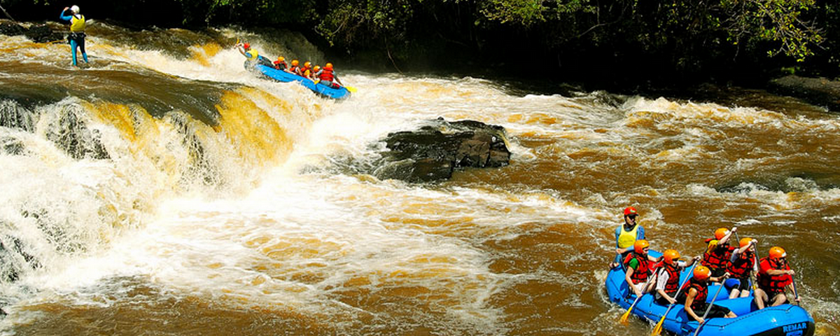 A imagem mostra pessoas praticando rafting