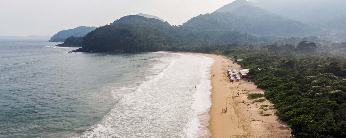 A imagem mostra a orla de uma praia com algumas pessoas