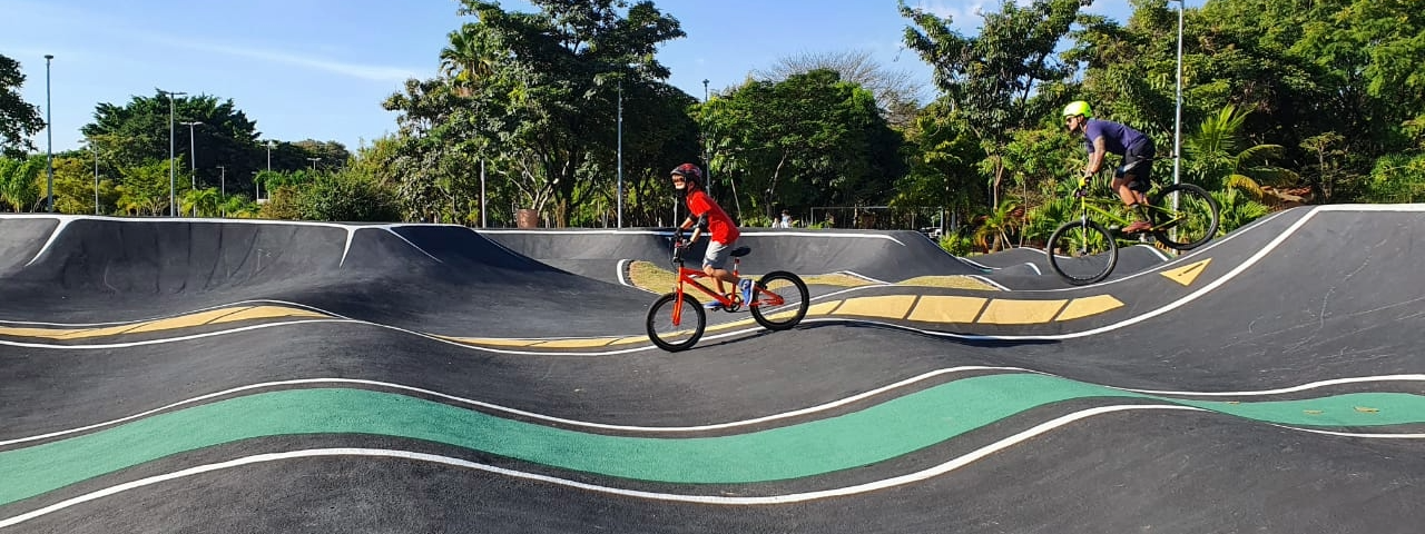 Pai e filho pedalando na pista do parque das bicicletas.