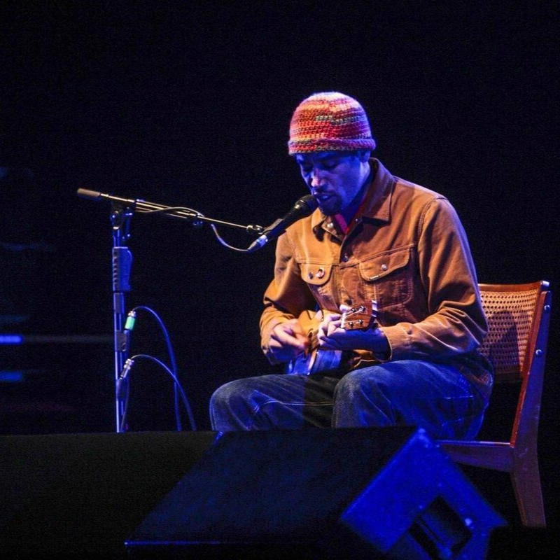 A imagem mostra o artista Ben Harper no palco durante o show