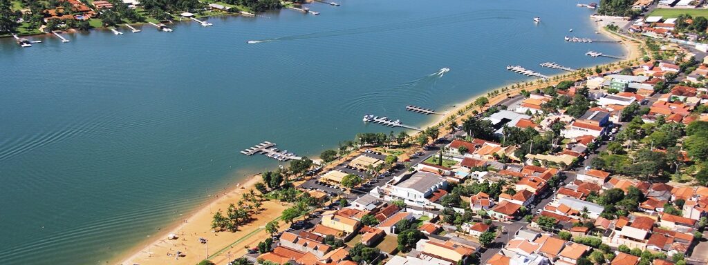 A imagem mostra a visão aérea de uma praia rodeada de casas