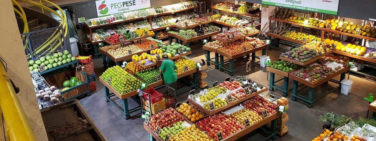 Parte interna do mercado de Pinheiros com diversas bancas de frutas.