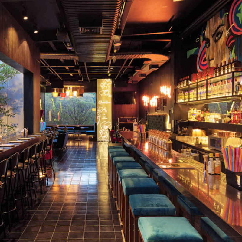 Ambiente interno do Caulí Bar em São Paulo, com sua decoração artística e iluminação vibrante, perfeito para um sextou com drinks autorais