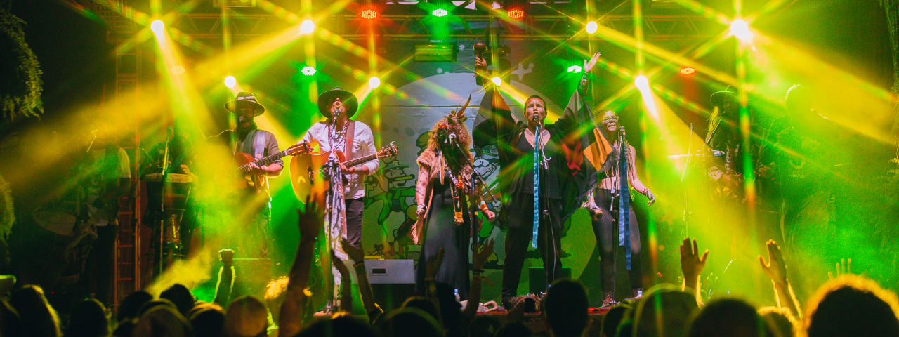 Banda se apresentando no palco do Festival da Lua Cheia, um evento multicultural no interior, ideal para curtir em junho