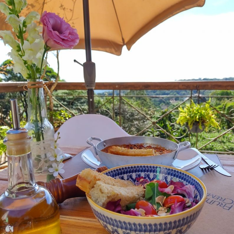 Mesa de café da manhã no Frutta & Crema, com vista para a natureza da Serra da Cantareira, um refúgio gastronômico em SP