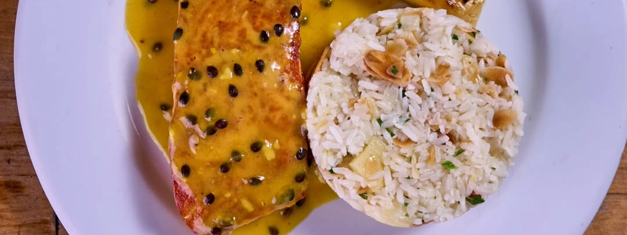 Prato refinado composto por arroz e salmão coberto com molho de maracujá, combinando elegância e sabor