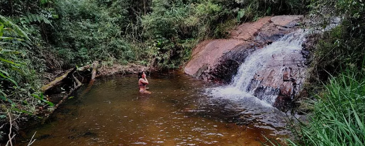 Turista tomando banho de cachoeira na Trilha das 7 Cachoeiras, em um momento de conexão com a natureza