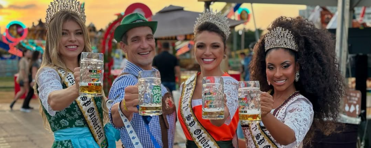Quatro pessoas segurando copos de cerveja no festival Oktoberfest, brindando em um clima de celebração