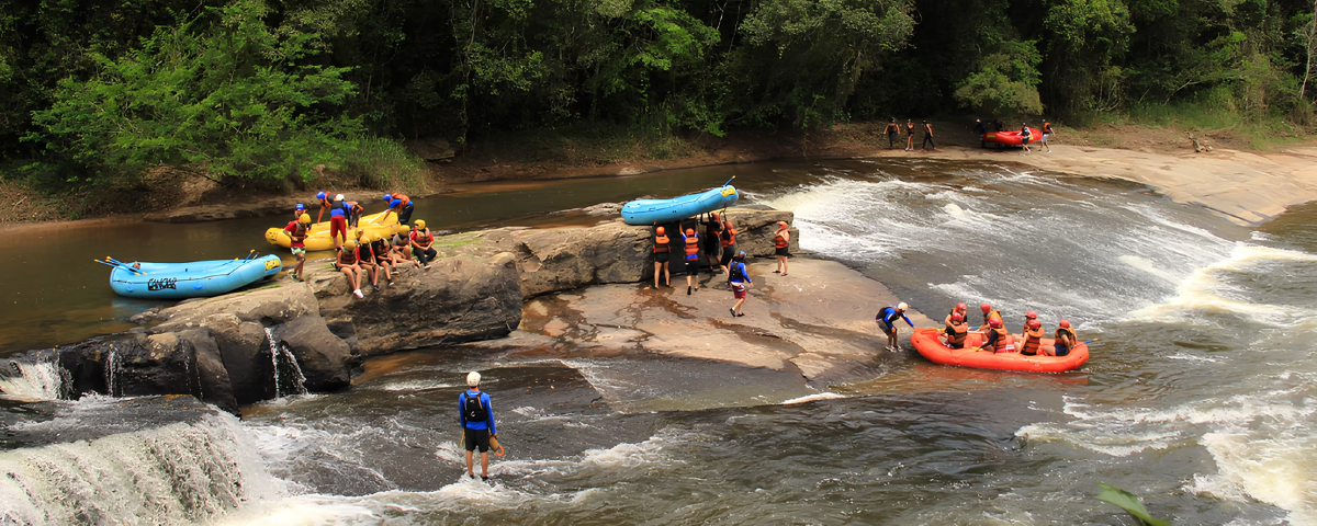 Grupo de pessoas praticando rafting em um rio cercado por vegetação natural