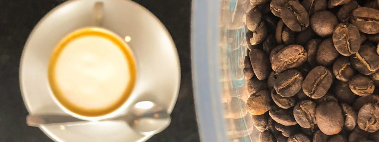 Xícara de café ao lado de grãos torrados, destacando a qualidade e o aroma intenso da bebida