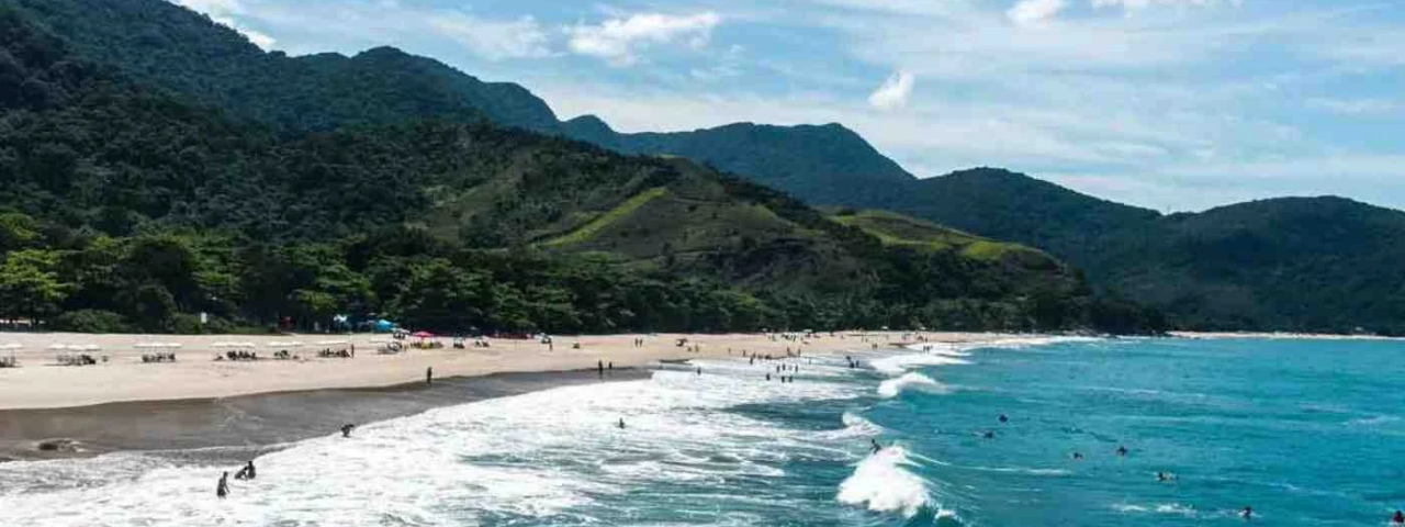 Praia de Santiago em São Sebastião, com areia clara, águas tranquilas e vegetação costeira. (Fonte: Viaje Leve / Divulgação)