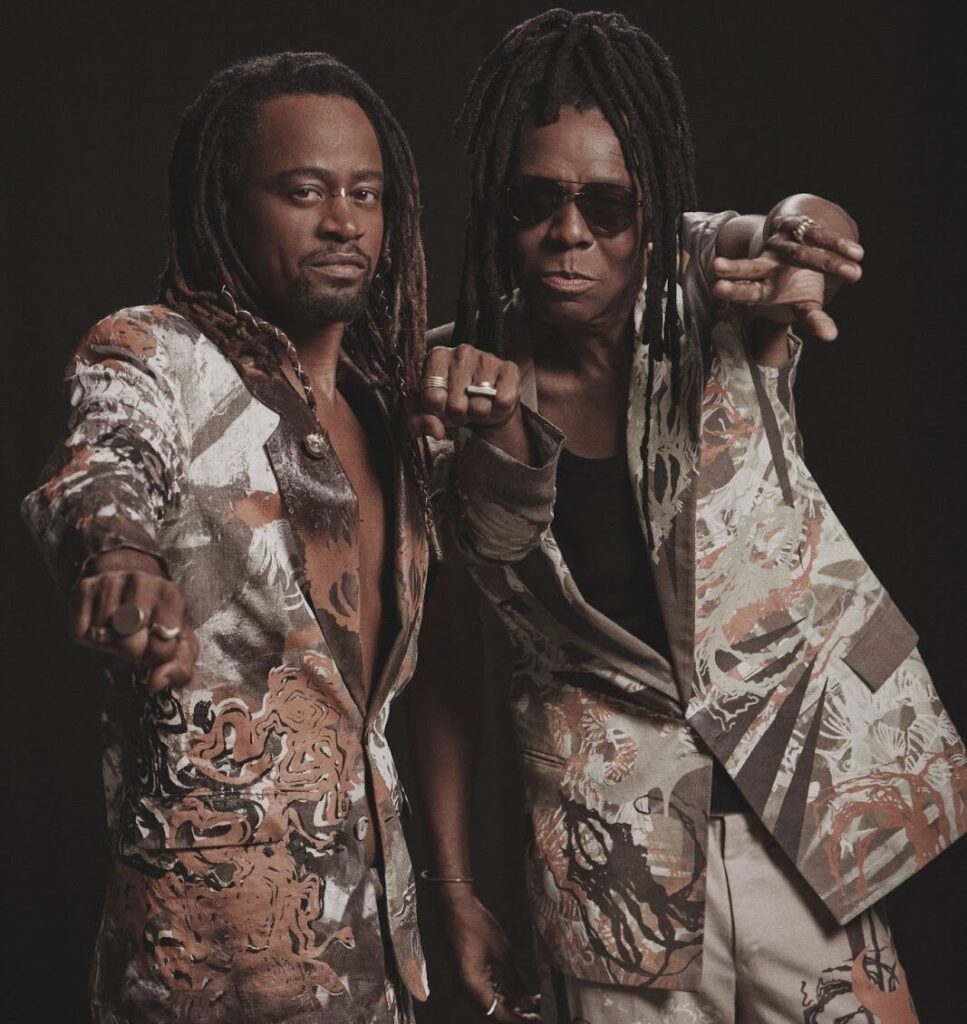 imagem mostra dois cantores do cidade negra com ternos 