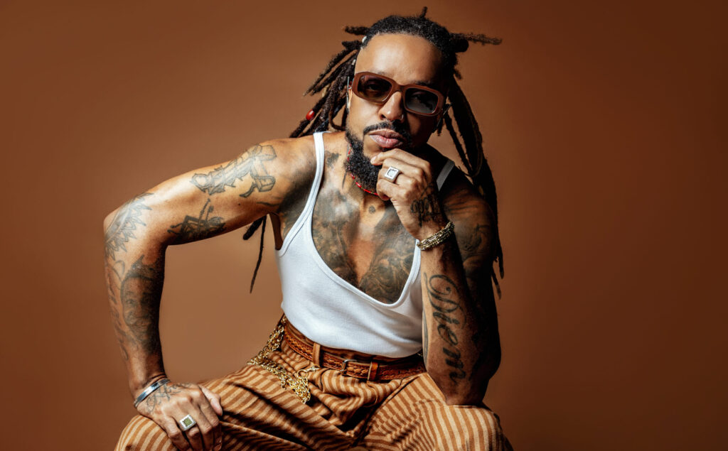 imagem cantor Rael sentado com óculos escuros