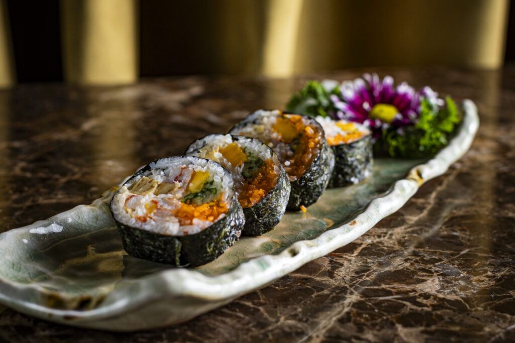 imagem mostra um prato com comida japonesa decorado com flor
