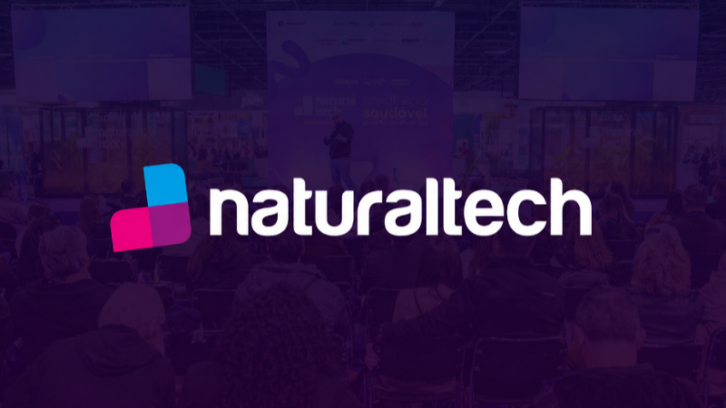 Imagem promocional da Naturaltech mostra auditório durante evento no Distrito Anhembi, com público assistindo a uma apresentação em palco ao fundo e logotipo “naturaltech” centralizado sobre filtro em tons de roxo.
