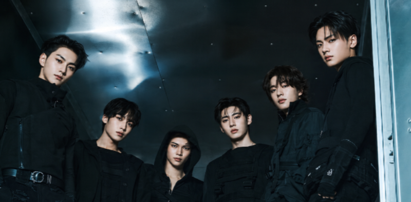 Fotografia promocional do grupo sul-coreano ENHYPEN. Os integrantes aparecem em ambiente com iluminação escura e tons azulados, vestindo roupas pretas e posicionados diante da câmera em composição que destaca a estética contemporânea e performática do grupo.