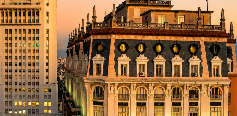 Dia do Cinema Brasileiro: vista do Edifício Martinelli ao entardecer, na região central de São Paulo. A construção histórica se destaca entre os prédios da cidade, com fachada iluminada e arquitetura característica do início do século XX.