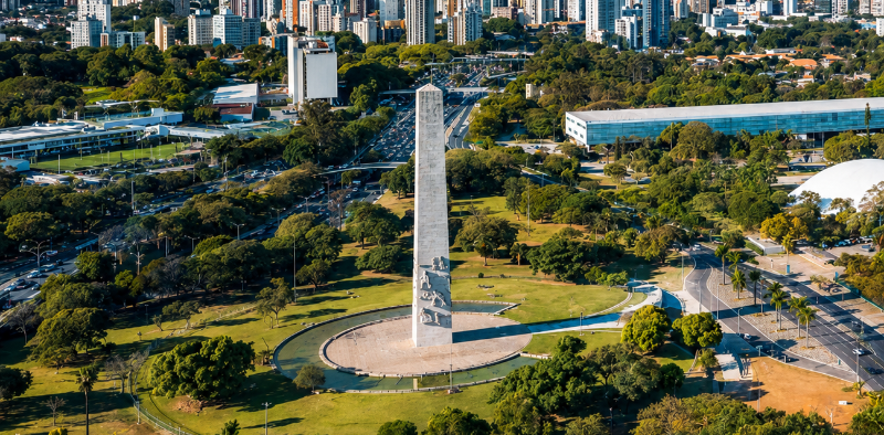 No contexto do Dia do Cinema Brasileiro, vista aérea do Obelisco do Ibirapuera, um dos marcos históricos de São Paulo. O monumento aparece cercado por áreas verdes, com a paisagem urbana da capital paulista ao fundo.