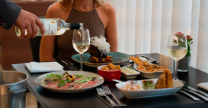 imagem mostra mesa de comida e vinho sendo servido