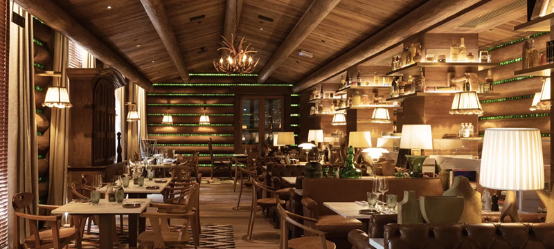 Ambiente interno do restaurante Blaise, no Rosewood São Paulo, com decoração em madeira, mesas preparadas para refeições e iluminação aconchegante.